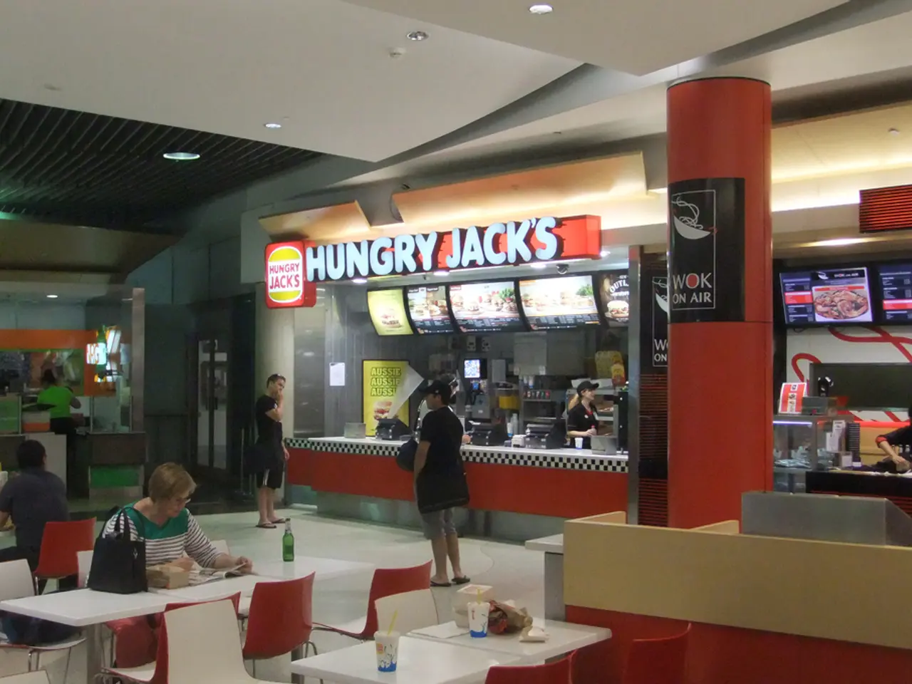 In a restaurant there is food ordering area where woman are standing to take order and on other...