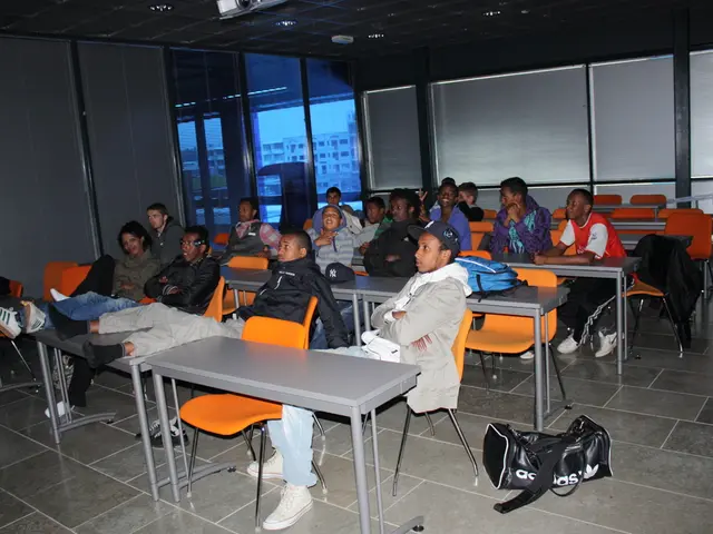 The image consists of few people sat on chairs in front of desk and staring, This seems to be a...